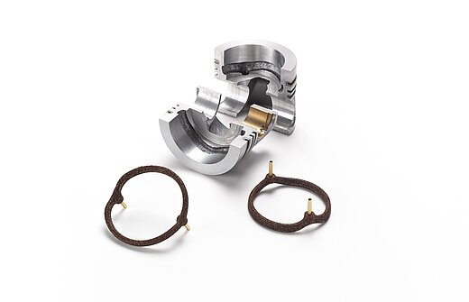 Ein silbernes Metallstück und braune Salzkerne für die Gießereitechnik