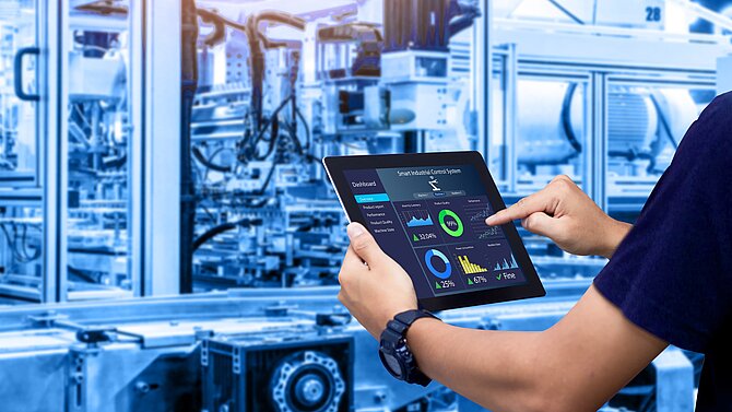 Man in hall with machines works on tablet