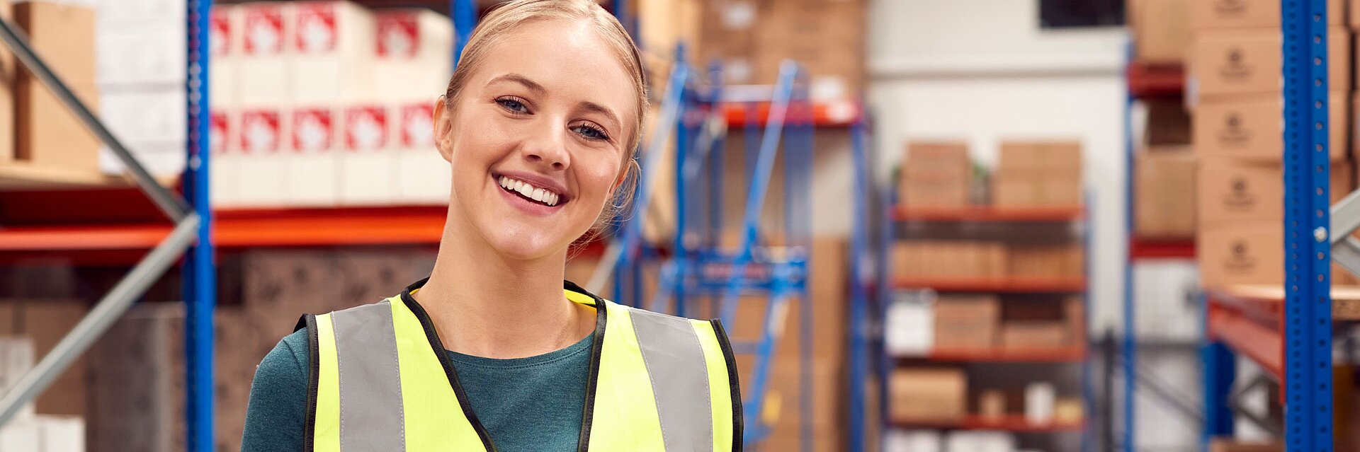 Porträt einer Arbeiterin, die eine Kiste in einem Lagerhaus hält