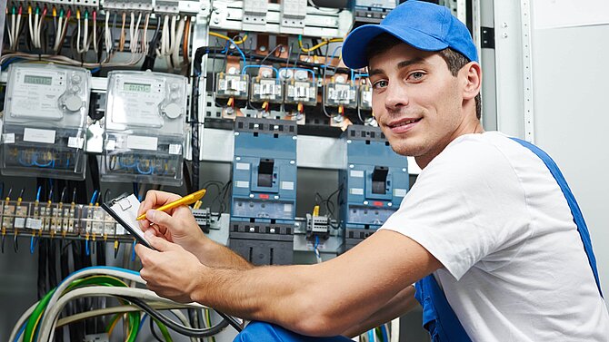 Auszubildender sitzt an einem Schaltschrank