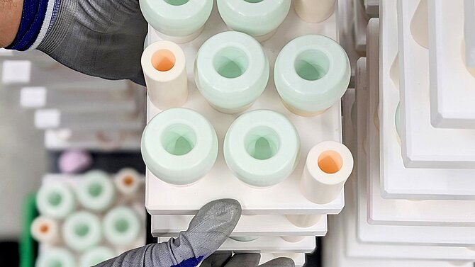 Ein CeramTec-Mitarbeiter bearbeitet in der Produktion eine Reihe grüner keramischer Rohlinge